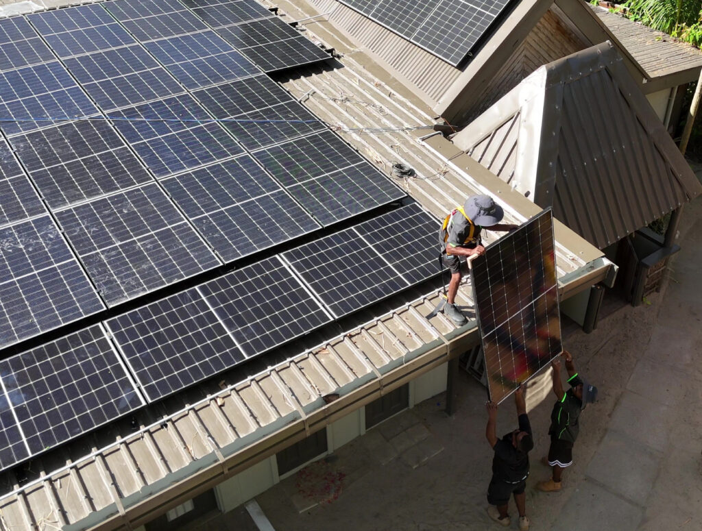 Fijian solar technicians installing panels and battery cabinets at Paradise Cove